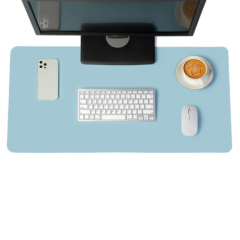 Blue desk mat and mouse pad used in an organised setup with desktop monitor, keyboard, and coffee cup.