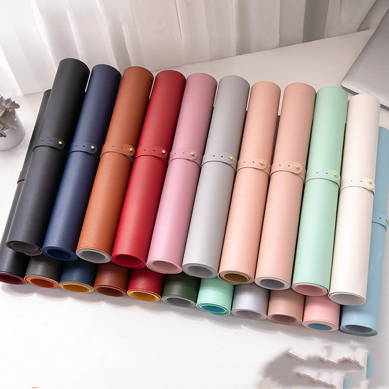 Rolled desk mats in a variety of colours neatly arranged on a white surface, showcasing stylish mouse pad options available at Cheeky Thangz.